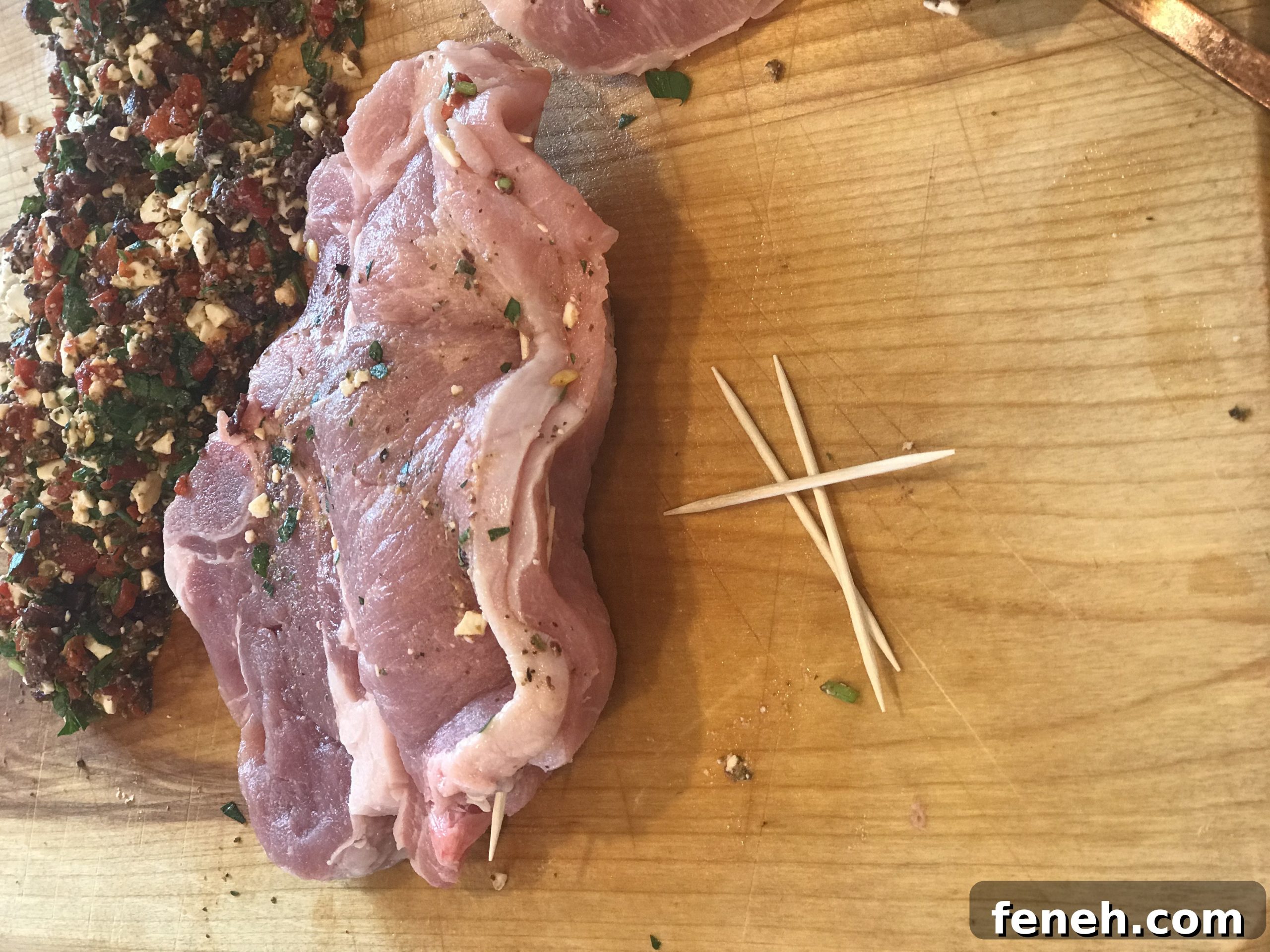 Filled pork chop with toothpicks holding the opening closed.