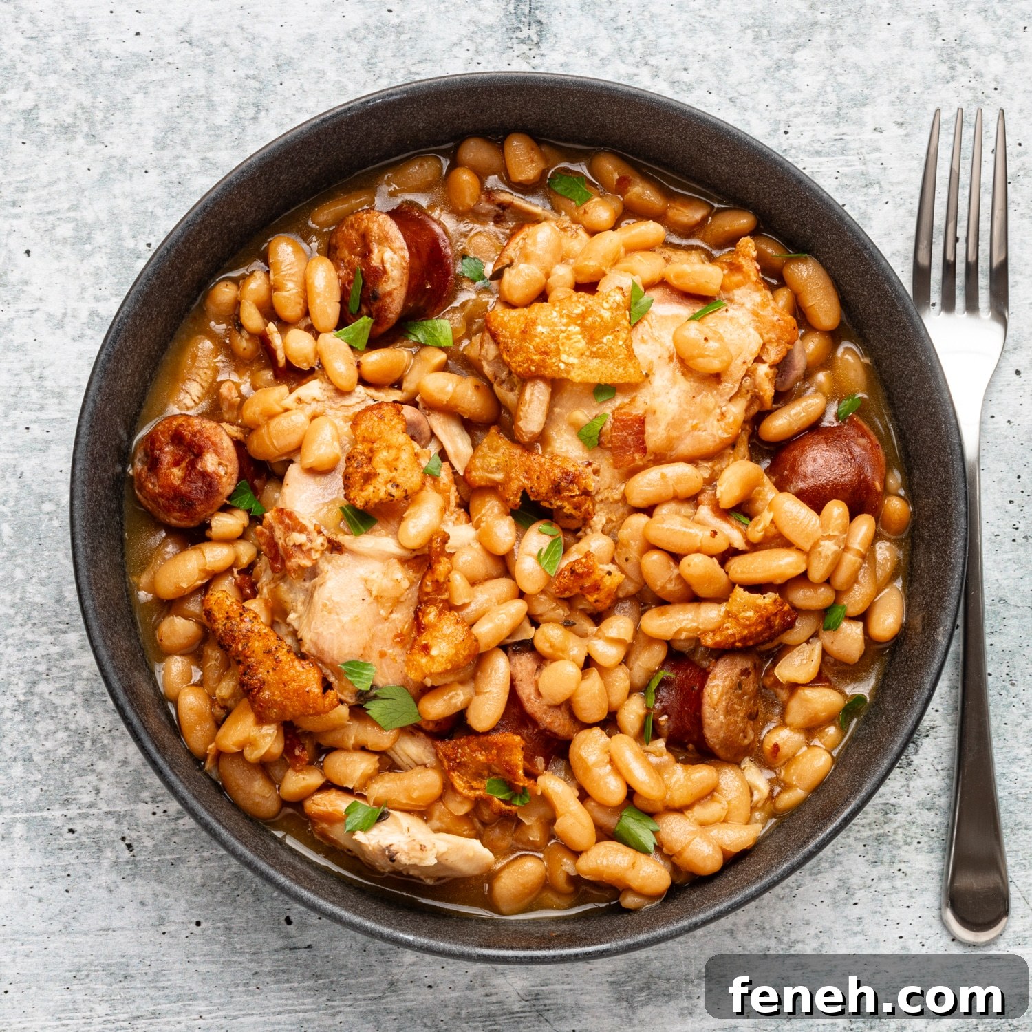 A serving bowl of Instant Pot cassoulet with crispy fried chicken skin and parsley for garnish.