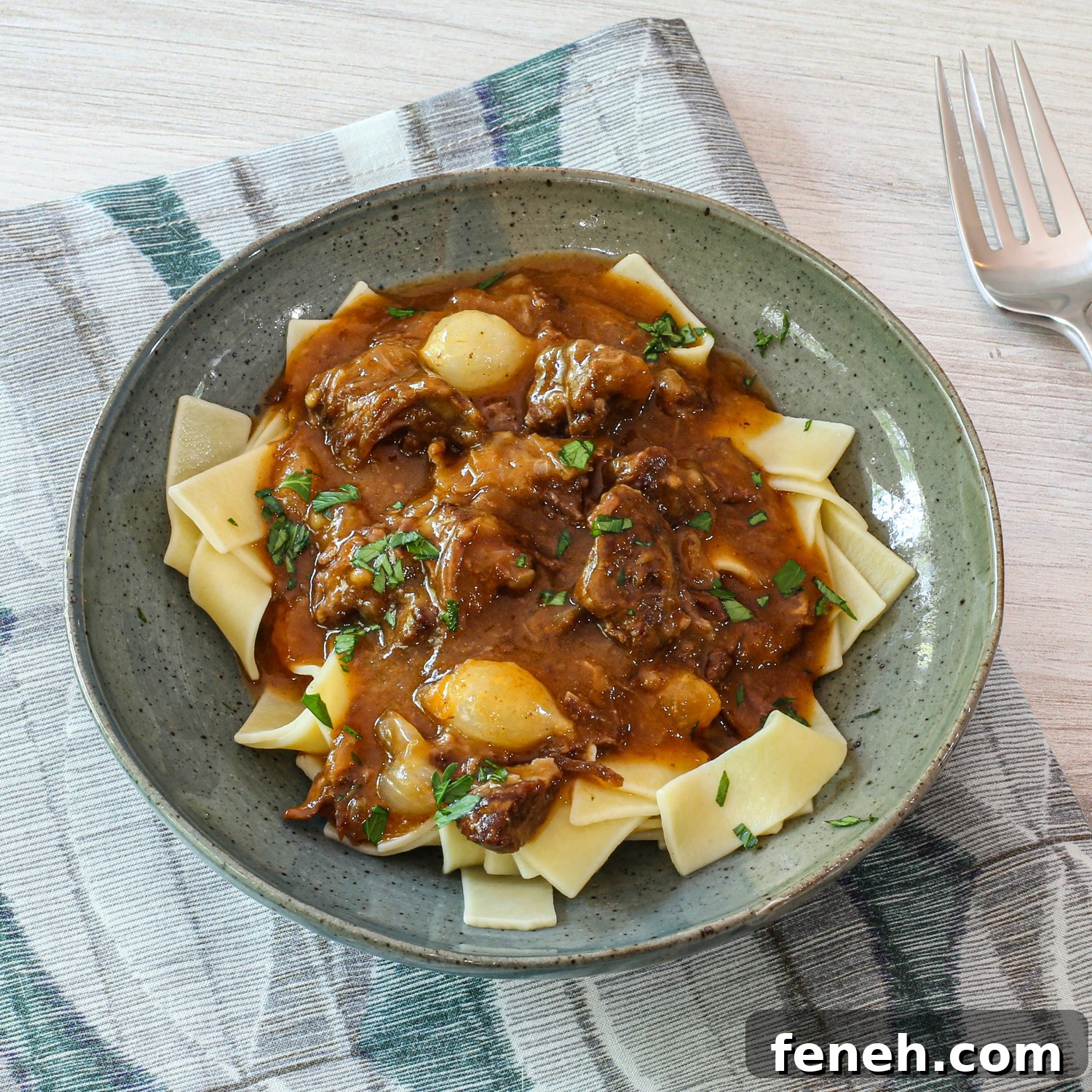 Instant Pot beef and beer stew (carbonnade) in a bowl with pappardelle pasta.