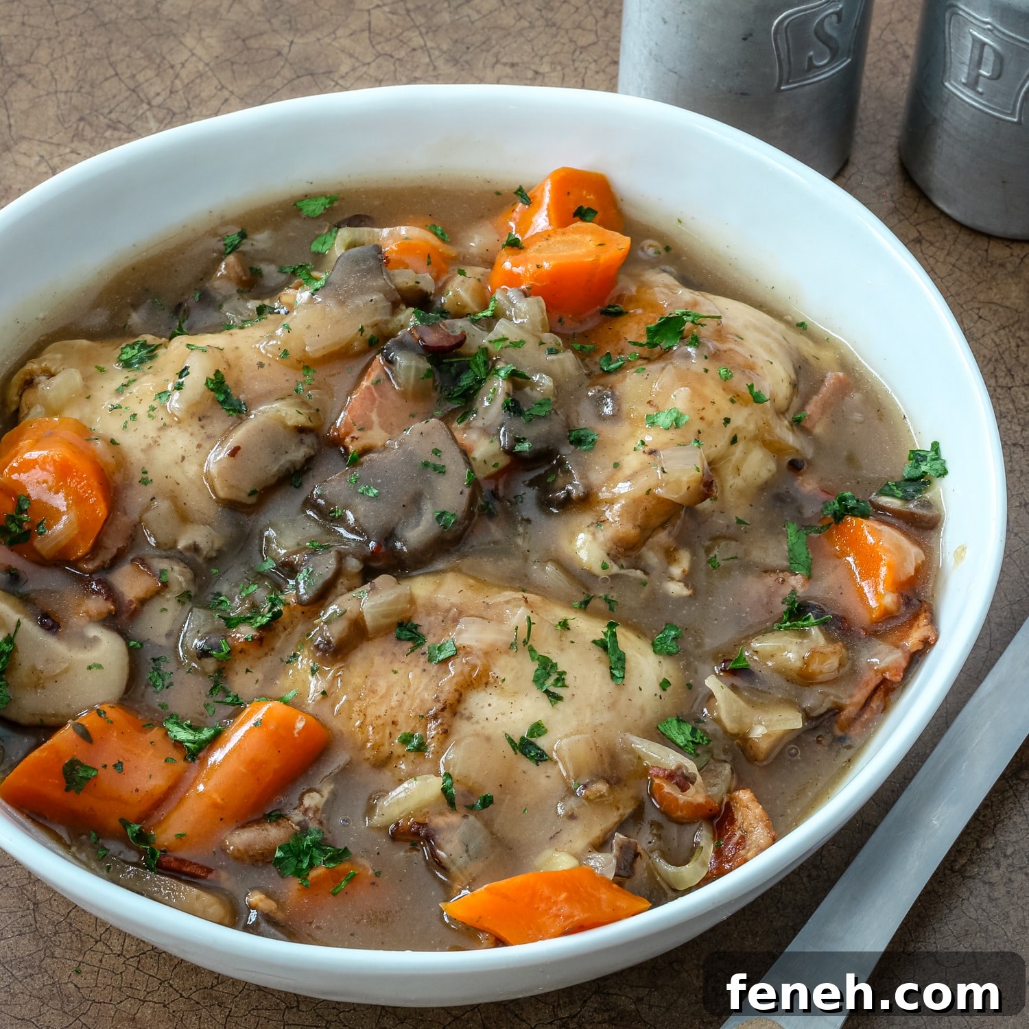 A serving bowl of Instant Pot white wine braised chicken thighs inspired by coq au vin blanc.