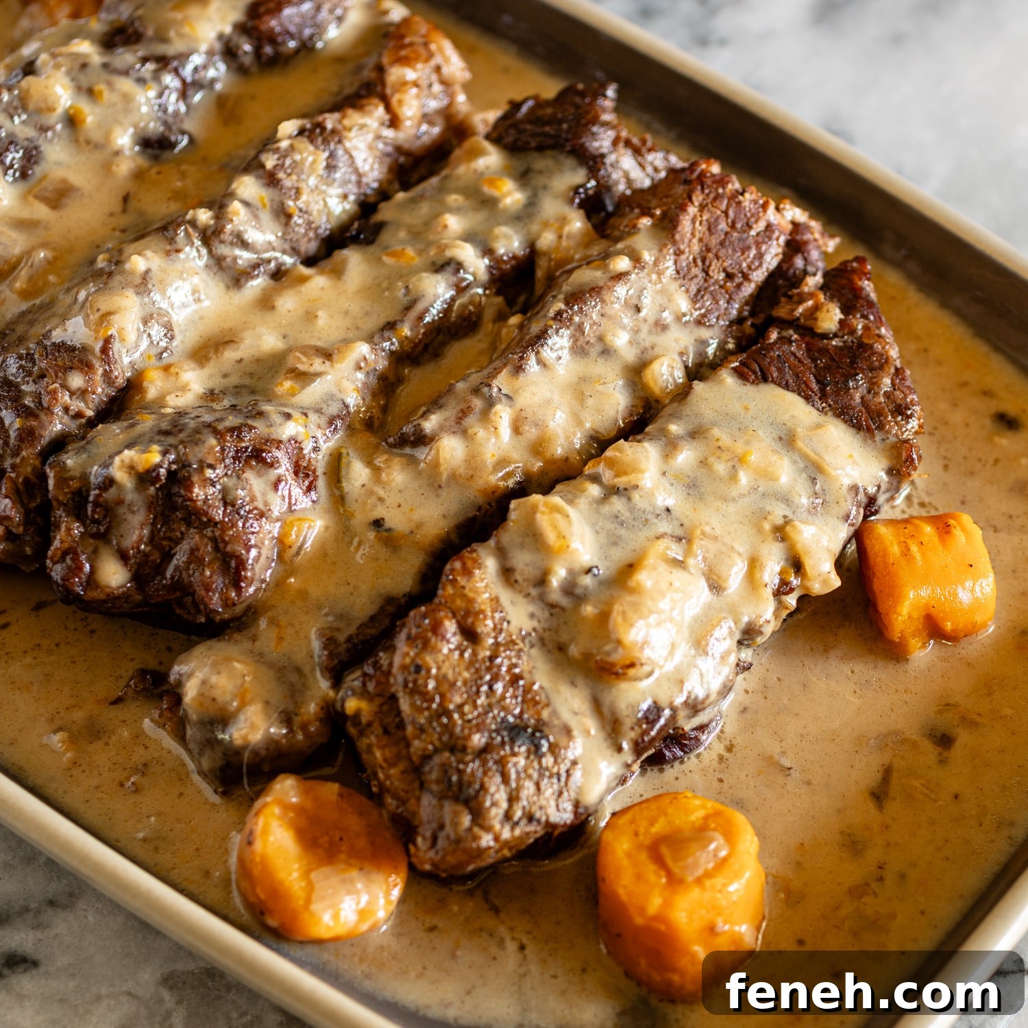 Instant Pot beef short ribs on a serving tray with carrots and sauce.