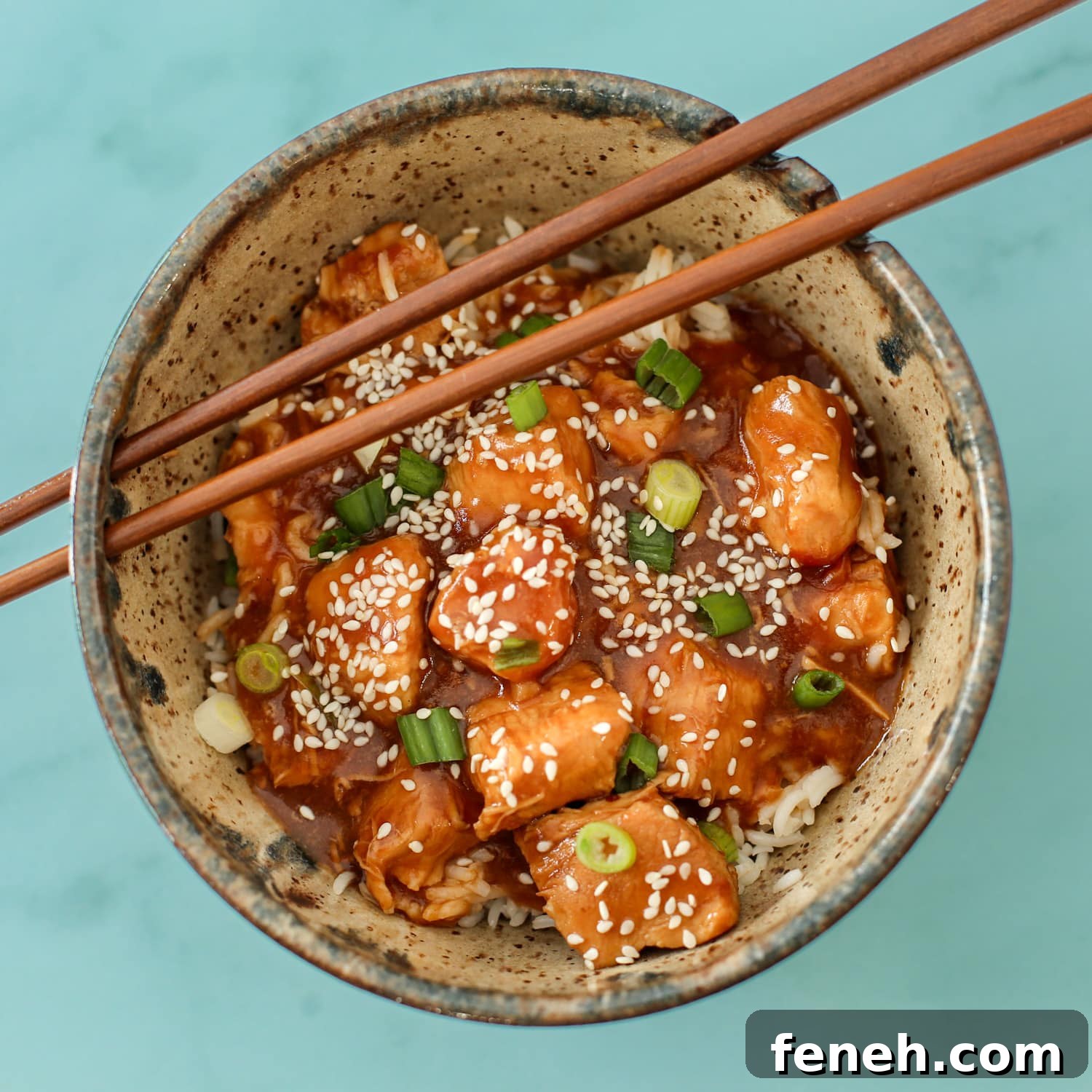 General Tso's chicken in a bowl with chopsticks.
