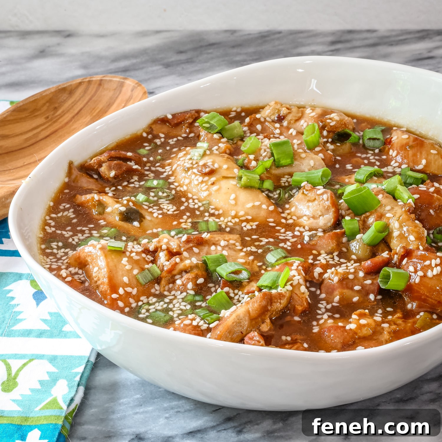 Honey sesame chicken in a serving dish with green onion garnish.
