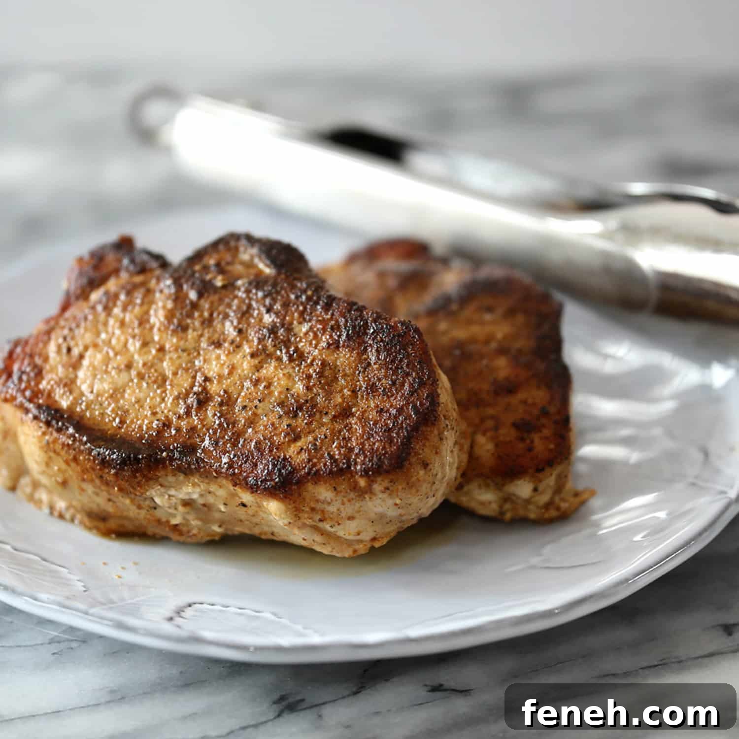 Instant Pot pressure cooker pork chops on a serving plate with tongs in the background.