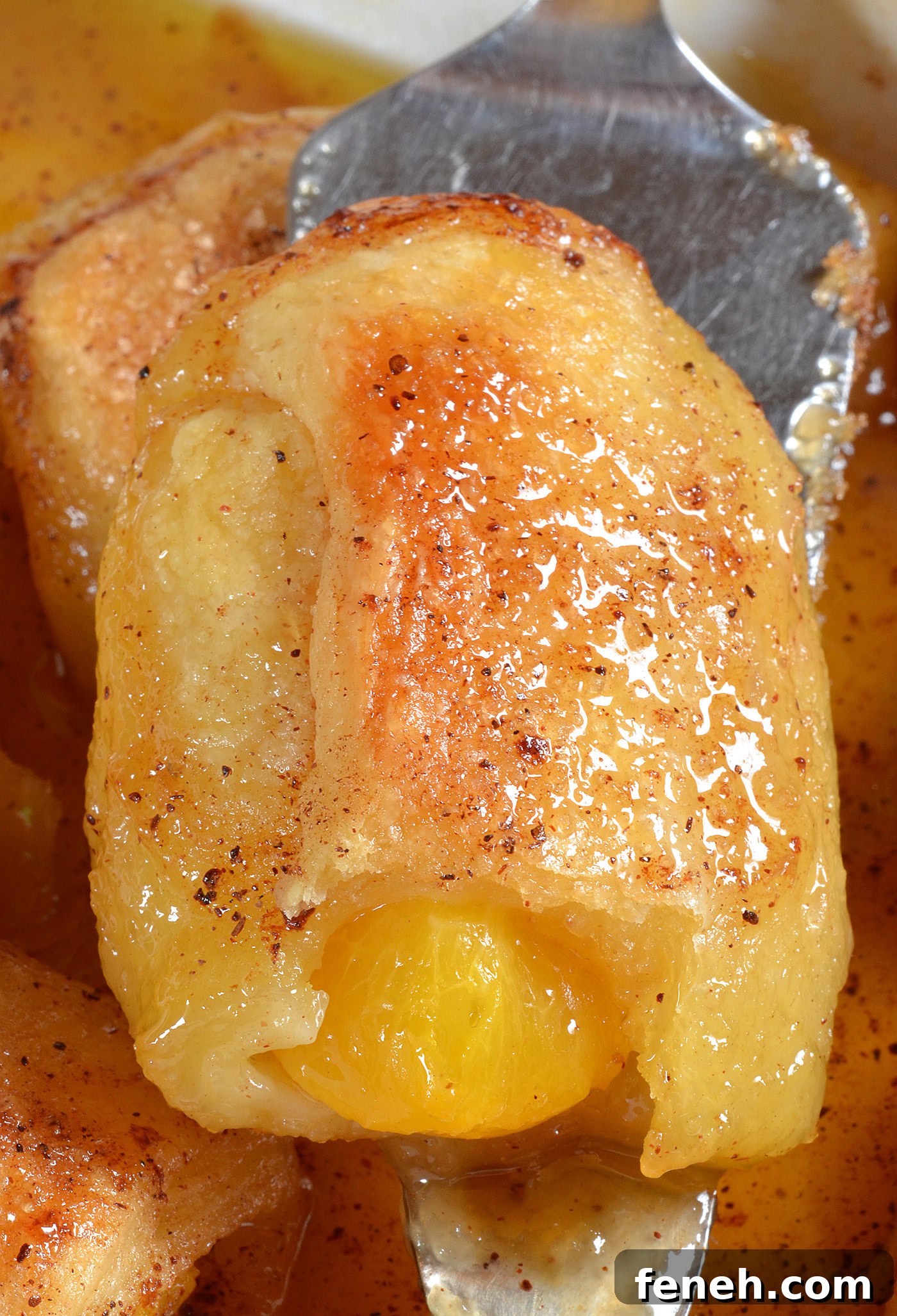 Peach dumpling with crescent roll dough showing soft buttery texture and juicy peach filling inside