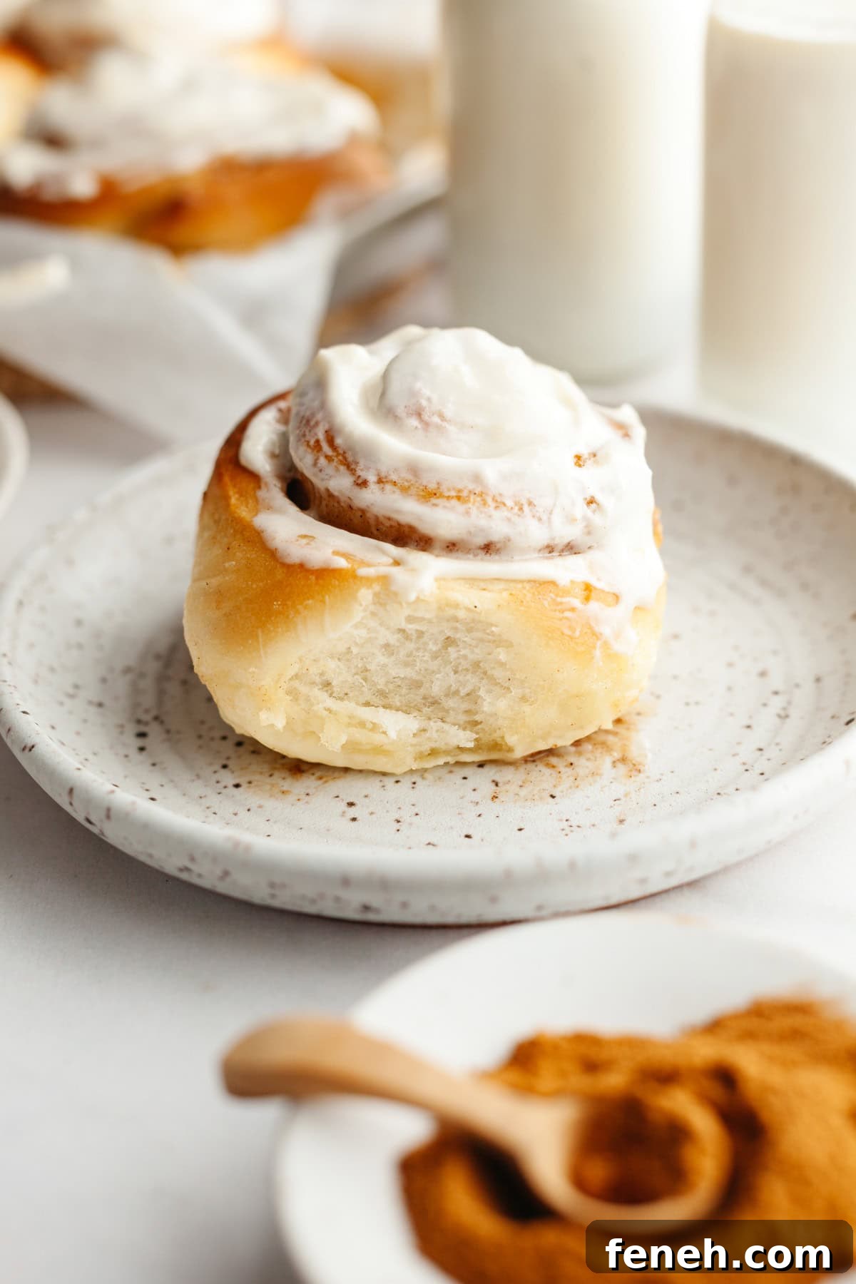 A cinnamon roll with cream cheese icing on a small plate.