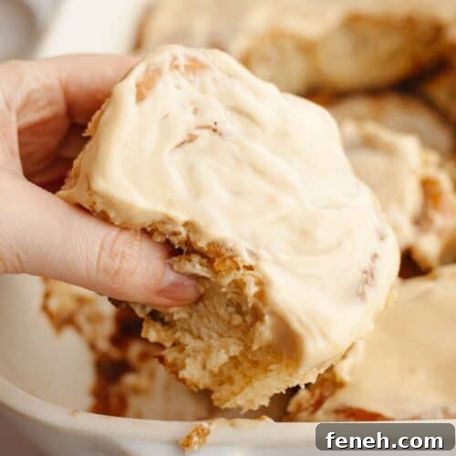 A hand grabbing a cinnamon coffee roll.
