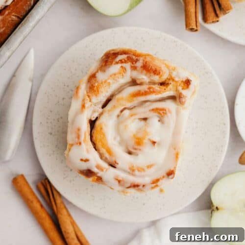 A cinnamon roll with apple pie filling on a small plate.