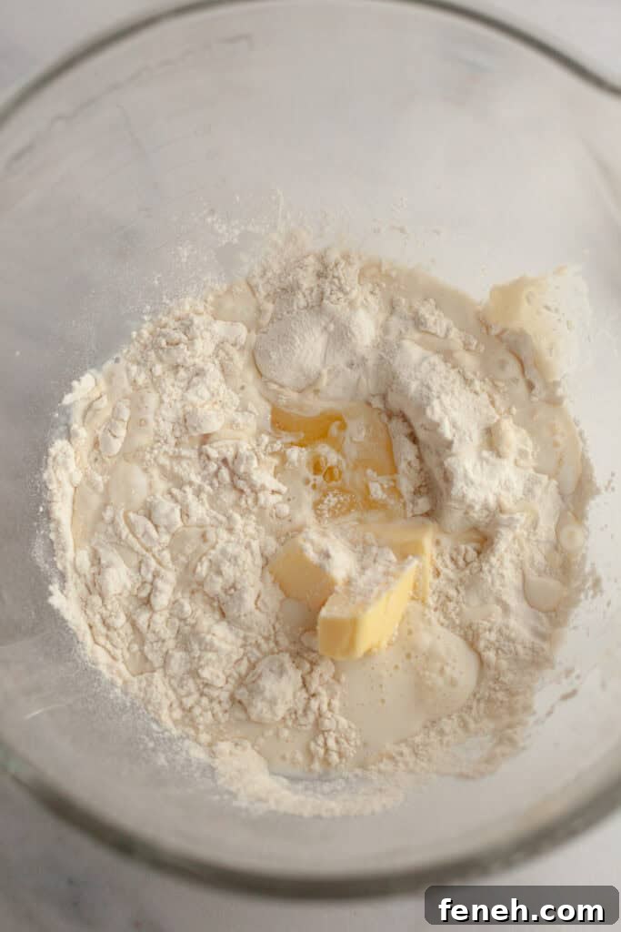 A glass bowl with flour, butter, milk, and yeast.
