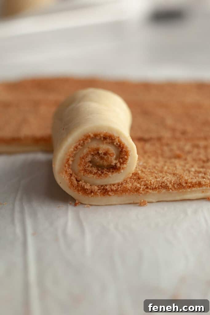 A cinnamon roll being rolled up.