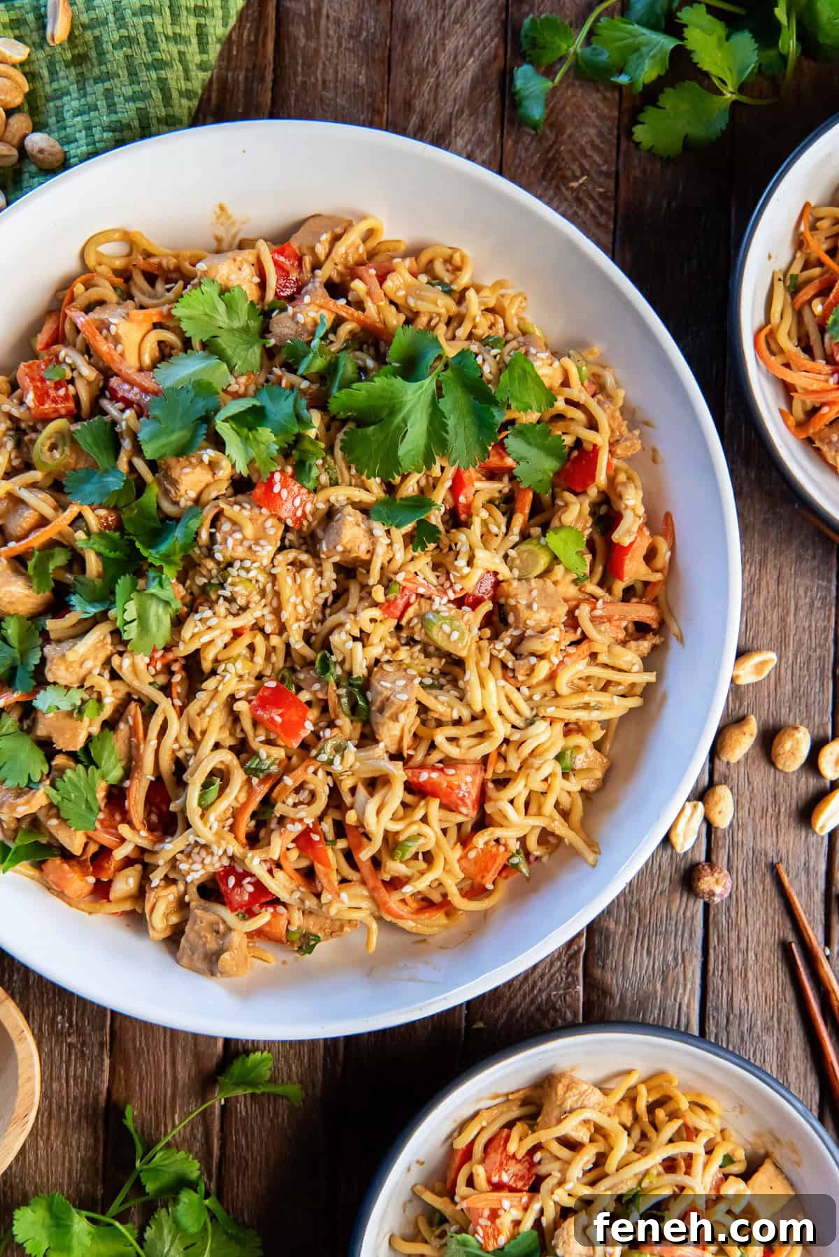 Peanut noodles with chicken in a large white bowl topped with cilantro.