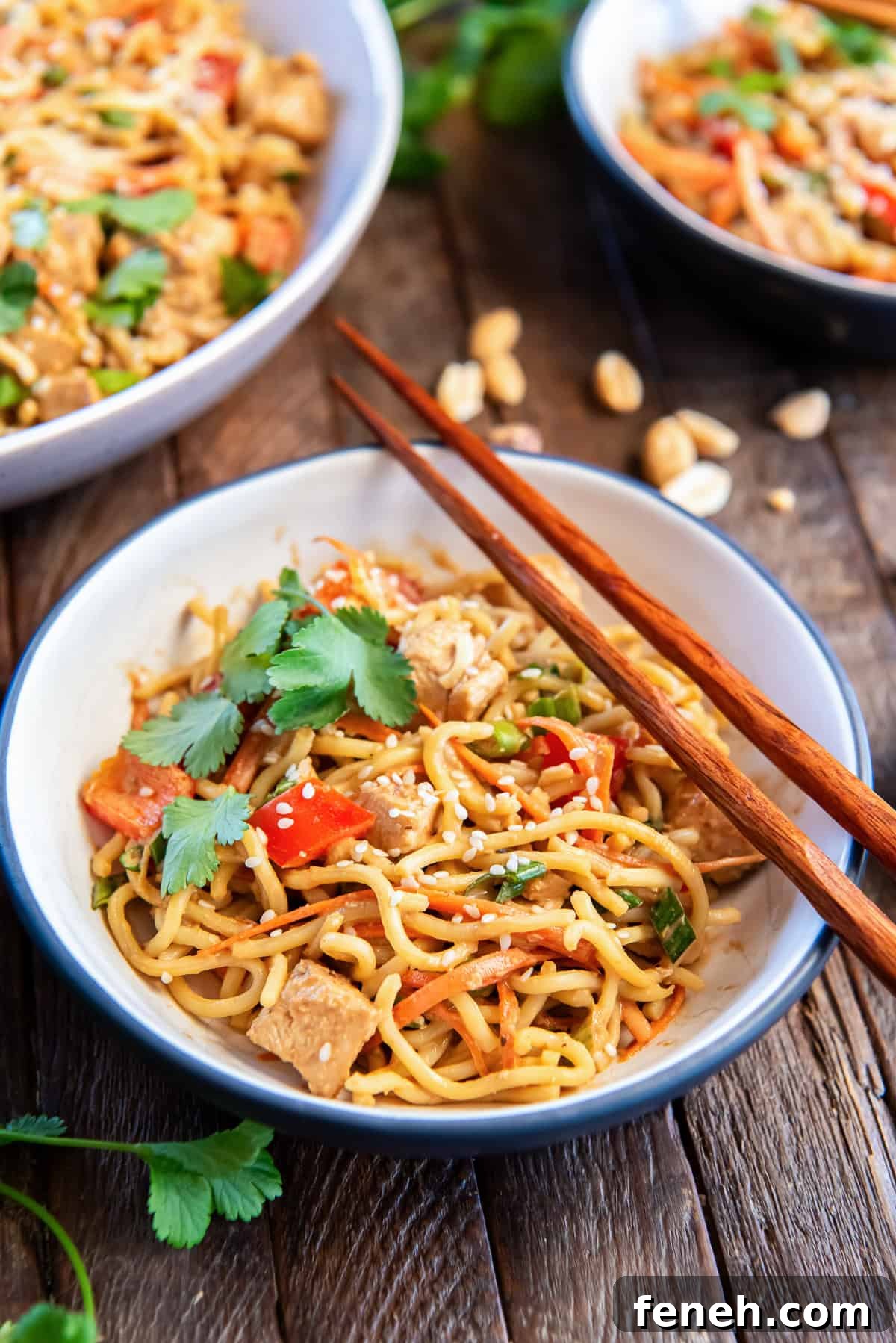 A serving of peanut noodles with chicken in a small white bowl with chopsticks resting on top.
