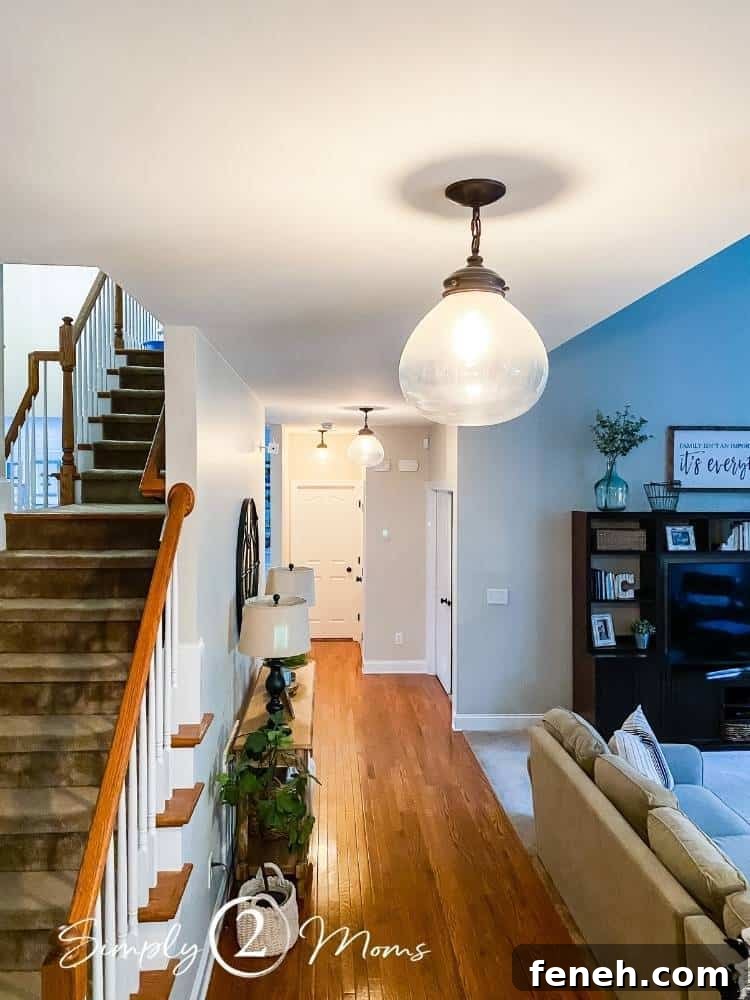 three hanging glass light fixtures before cleaning in hallway of open concept room stairs to left of hall