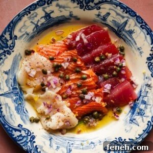 Colorful sashimi with capers and red onion on a decorative blue plate.