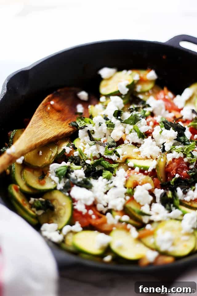 Sautéed zucchini, tomatoes, basil, and feta in a skillet.
