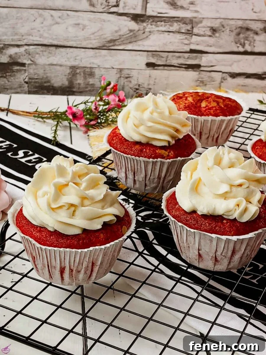 Cream cheese frosting on top of red velvet muffin placed on cooling rack.