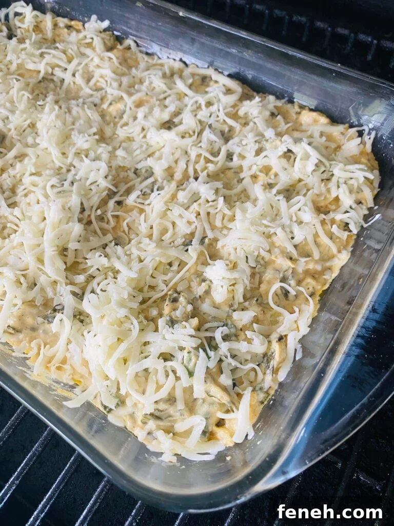 adding more cheese to the dip on the smoker