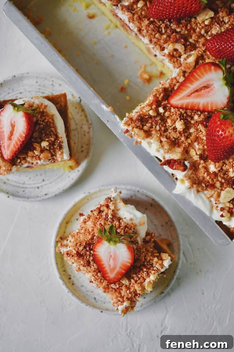 A couple slices of Strawberry Crunch Cake removed from the pan with a fresh strawberry on top.