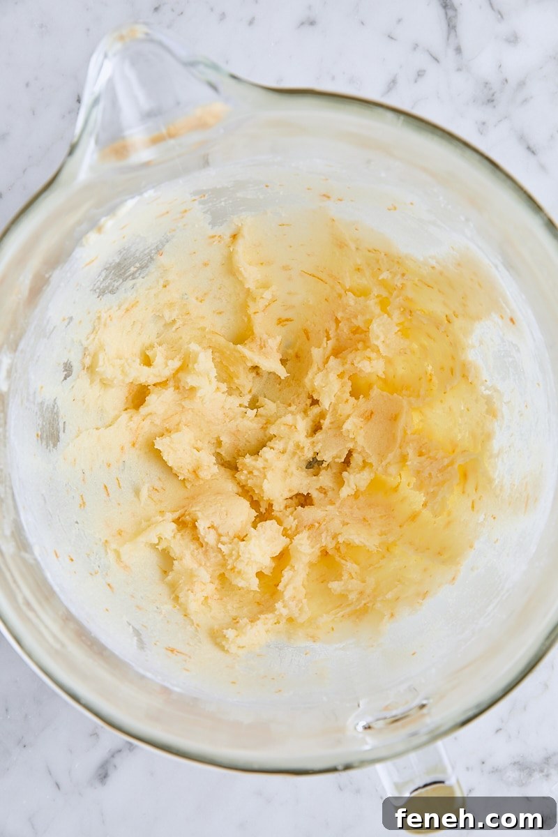 Softened butter and orange-sugar mixed together in glass mixing bowl