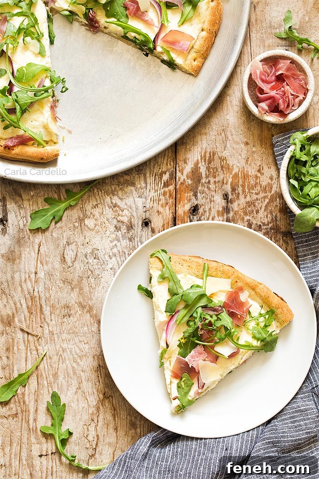 Slice of prosciutto pizza on a white plate