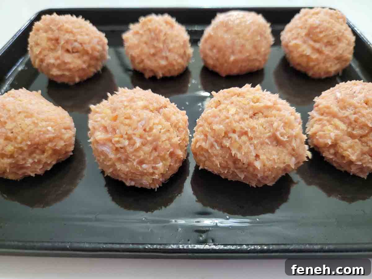 8 ground turkey meatballs on a baking sheet.