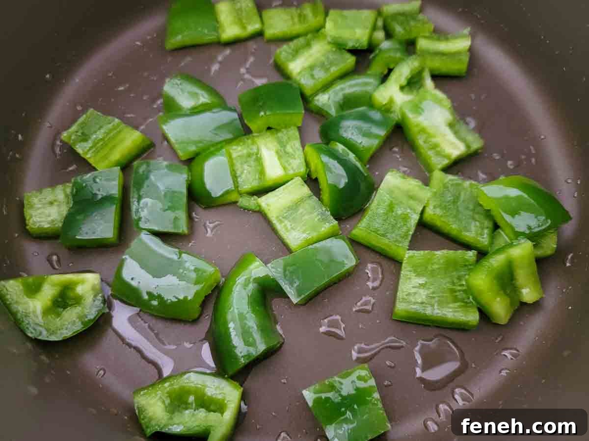 dice green pepper cooking in a pan.