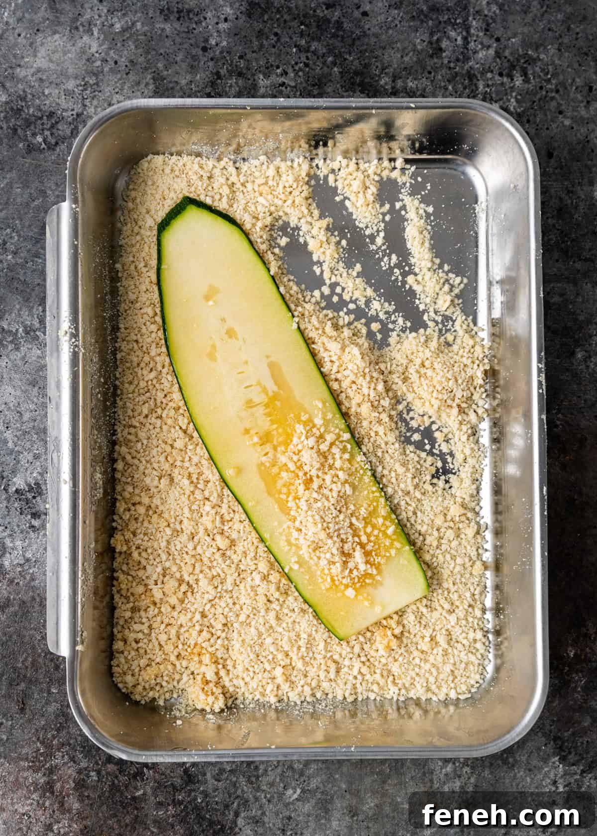 overhead process shot: dipping a slice of zucchini in breadcrumbs and parmesan