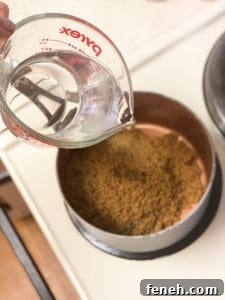 Water being poured into a saucepan with brown sugar
