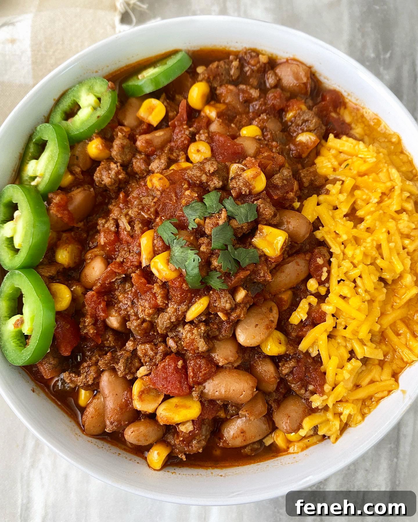 close up of overhead shot of taco chili in a white bowl with a jalapeno with cheese