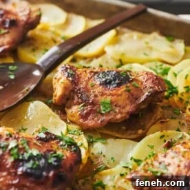 Spoon resting on a baking sheet of Roasted Marinated Chicken and Potatoes.