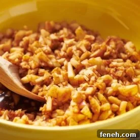 Homemade charoset in yellow bowl with wood spoon.