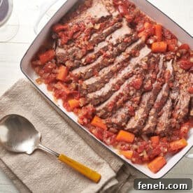 Jewish-style brisket in white dish on table with serving spoon.