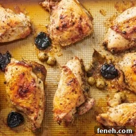 Chicken Marbella on a lined baking sheet.