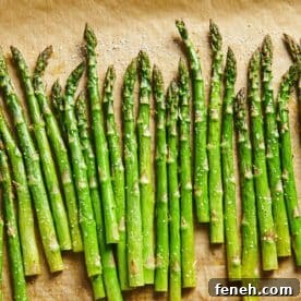 Parchment paper with a line of Roasted Asparagus.