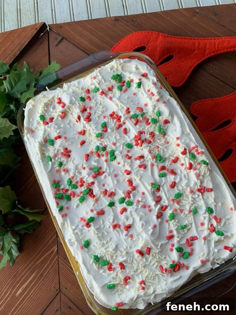 The egg nog layer cake with festive whipped cream frosting and Christmas sprinkles in a glass baking dish