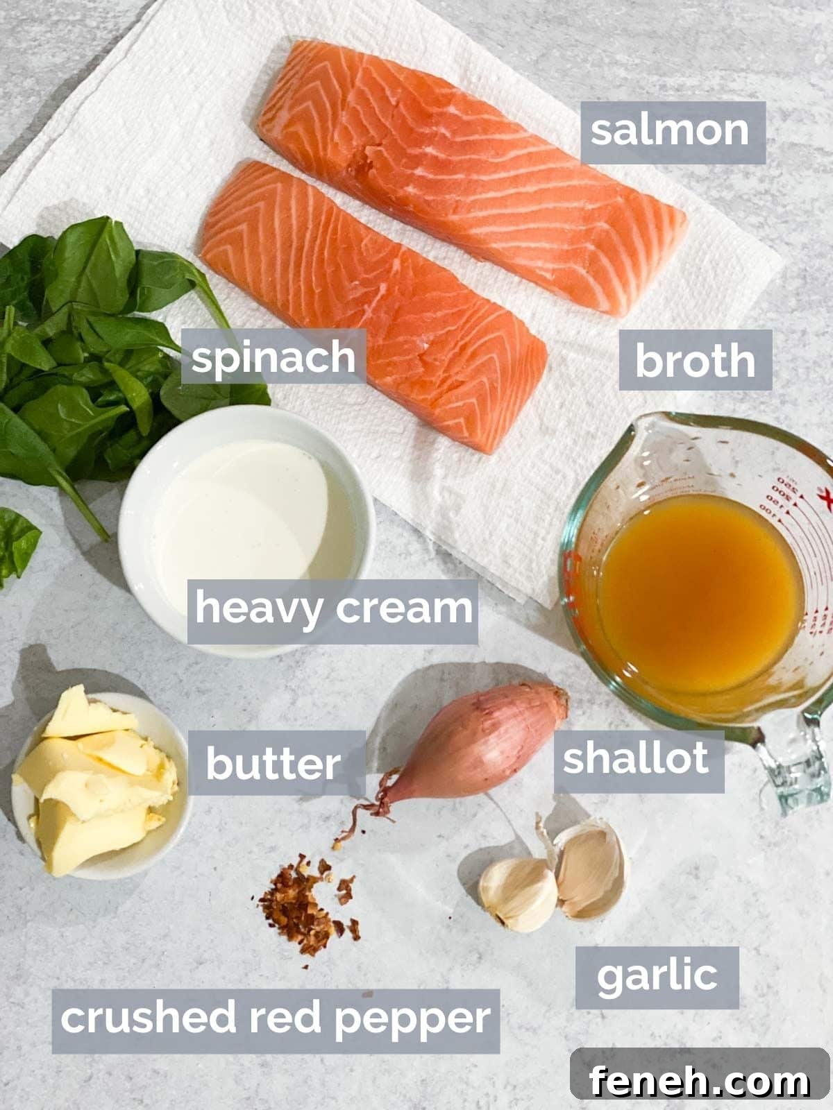 Salmon, spinach, broth, cream, butter, garlic, and shallot on a table