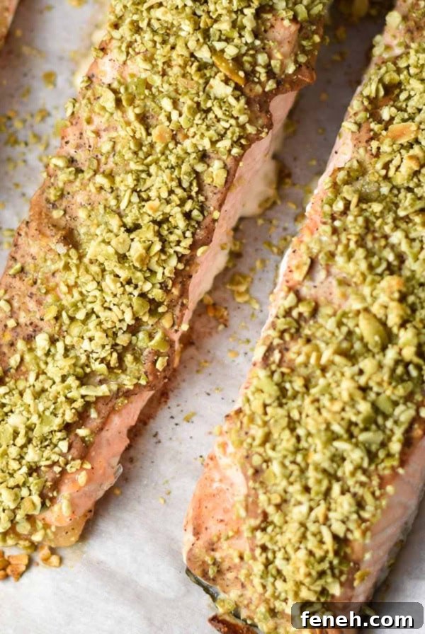 Three fillets of pepita crusted salmon on a baking sheet.