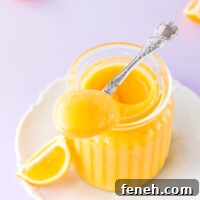 Microwave lemon curd in a ribbed glass jar, with a silver spoon on a purple background.