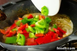 Green and Red peppers being added to the cast iron pan to cook