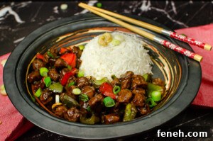 Vegan Kung Pao in a black bowl served with white rice and chop sticks on the side