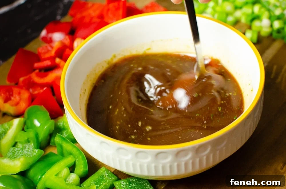 Vegan Kung Pao sauce in a white bowl being stirred together with a silver spoon 