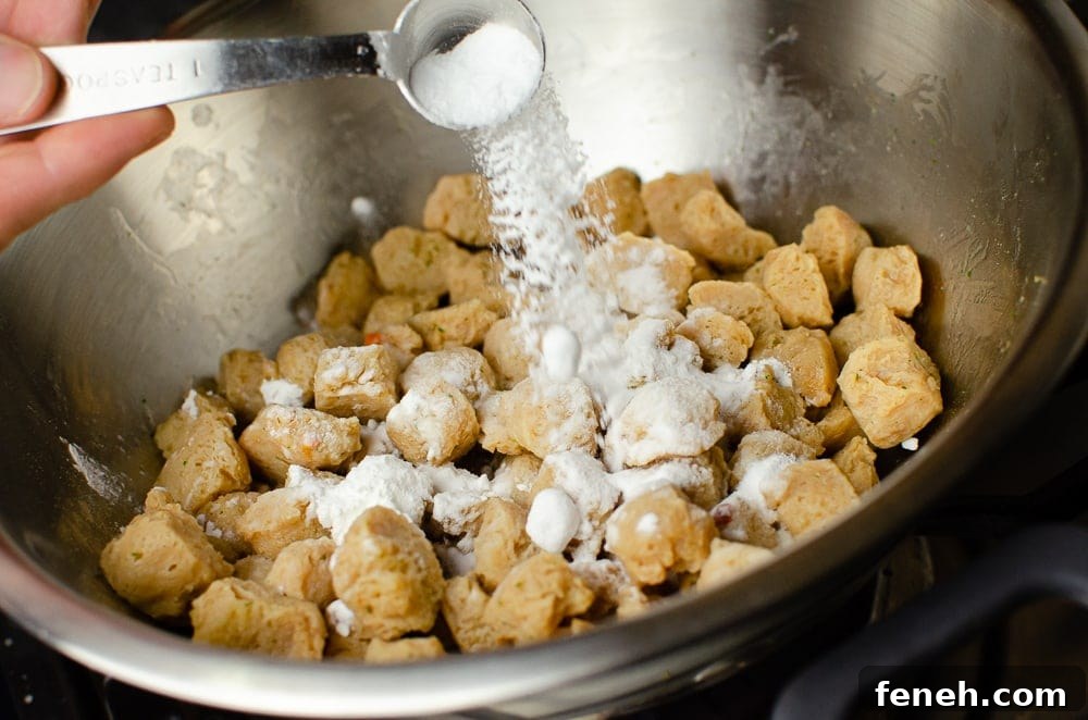 Cornflour and Bicarbonate of soda being added to the Textured Vegetable Protein in a silver bowl