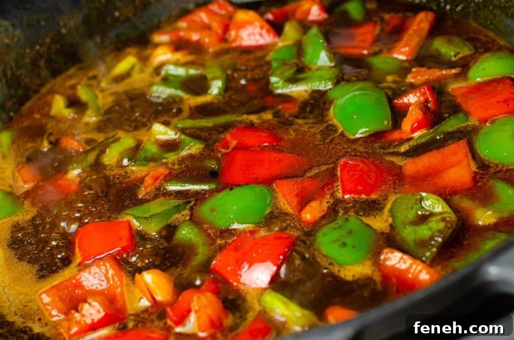 Vegan Kung Pao sauce with red and green peppers in a cast iron dis
