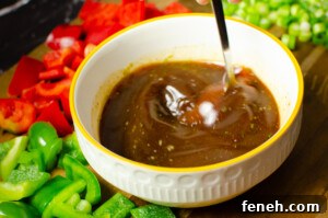 Vegan Kung Pao sauce in a white bowl being stirred together with a silver spoon