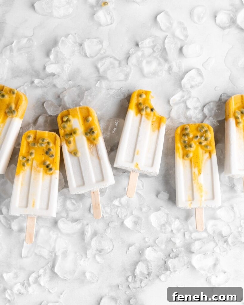 Tropical popsicles featuring mango, passion fruit, and coconut lay on a bed of ice