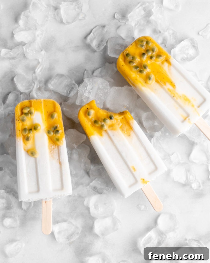Tropical popsicles featuring mango, passion fruit, and coconut lay on a bed of ice
