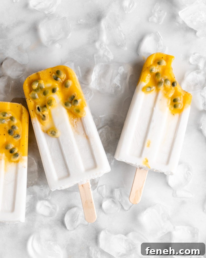 Tropical popsicles featuring mango, passion fruit, and coconut lay on a bed of ice