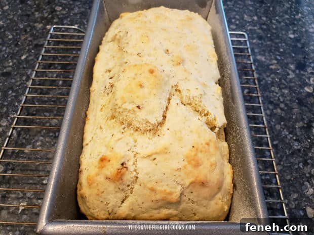 A loaf of golden brown sun-dried tomato Parmesan bread cools in pan after baking.