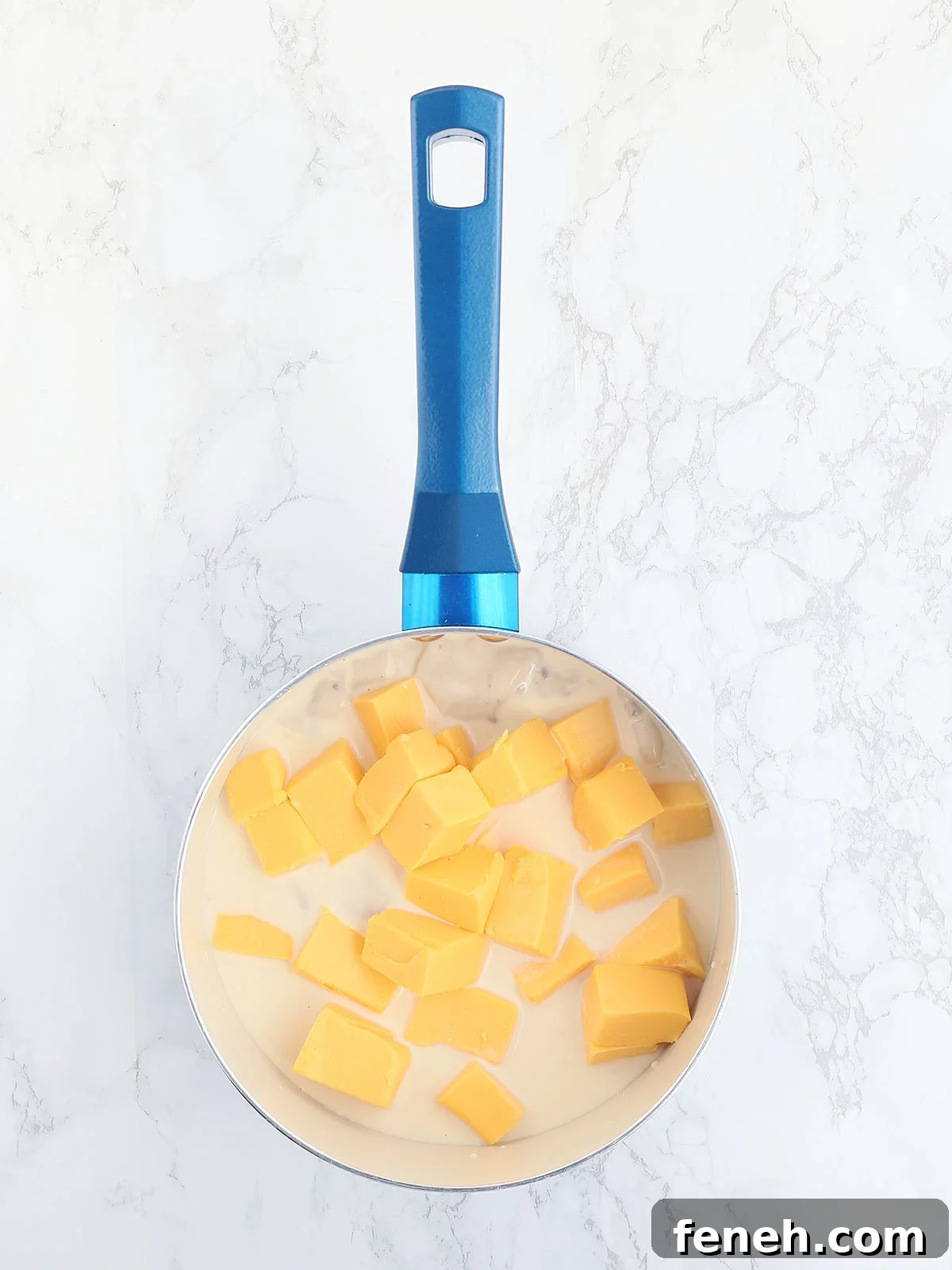 soup, milk and Velveeta cheese in a blue saucepan