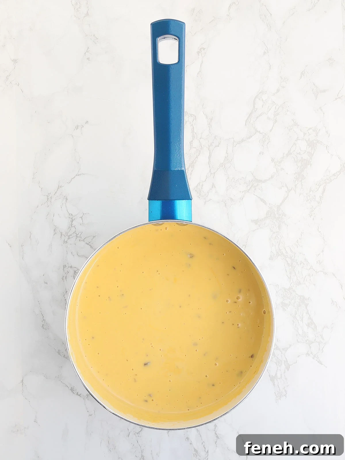 melted cheese sauce in a blue saucepan